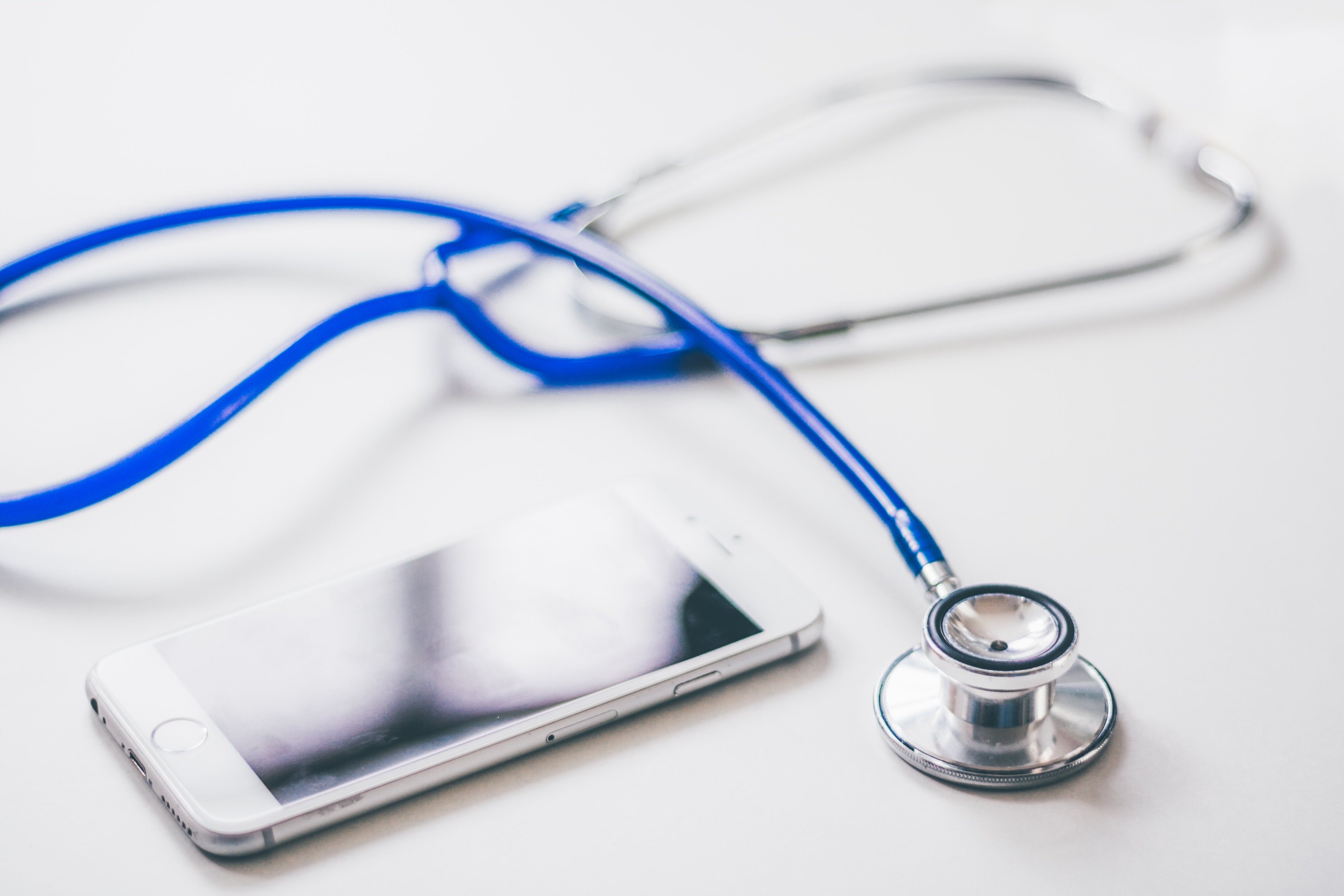 Blue stethoscope and iPhone on a table.