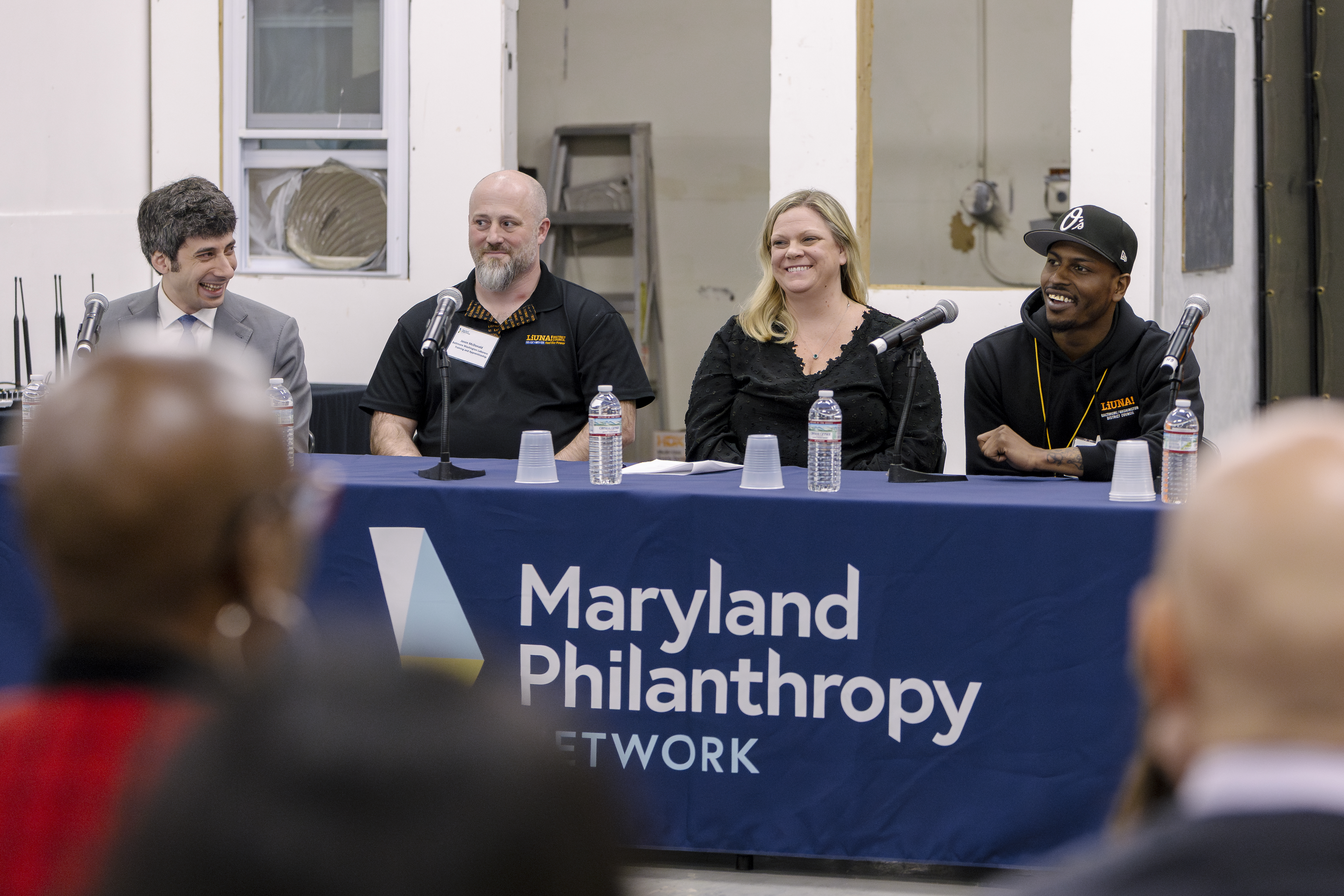 Four people are seated at a table speaking on a panel for a 2025 Baltimore Workforce Funder Collaborative event.