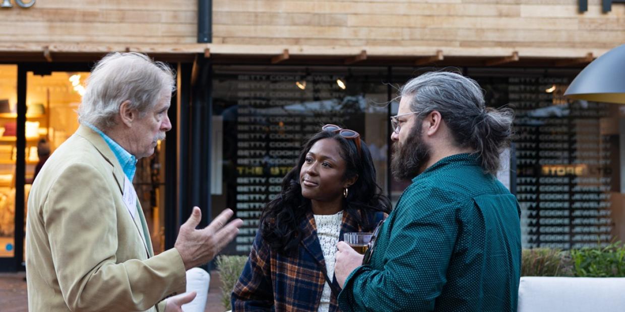 Three people chat with one another on an outdoor patio at the CEO Happy Hour in October 2024.