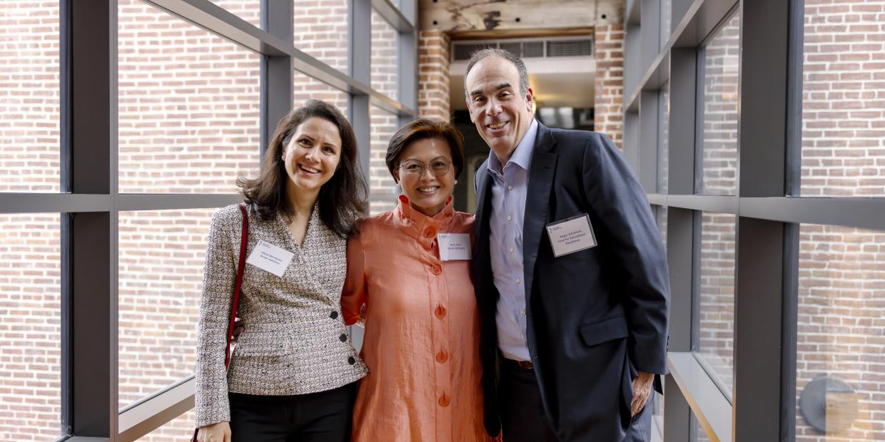 Three smiling people pose in a hallway with windows during the 2024 Annual Gathering.