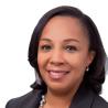 Headshot of a Black woman with shoulder length hair in a dark colored suit.